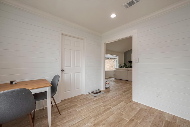 home office with ornamental molding, wood walls, light wood-type flooring, and visible vents