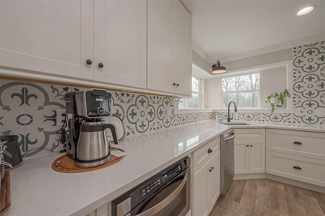 kitchen featuring a sink, light wood-type flooring, white cabinetry, and crown molding