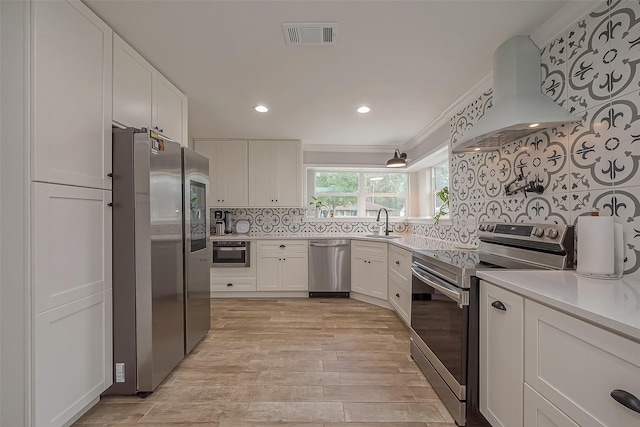 kitchen with a sink, visible vents, white cabinetry, appliances with stainless steel finishes, and island exhaust hood