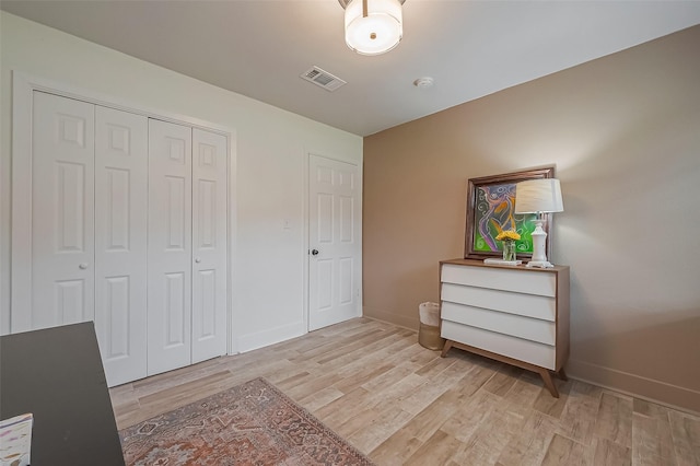 bedroom featuring baseboards, a closet, visible vents, and light wood-style floors