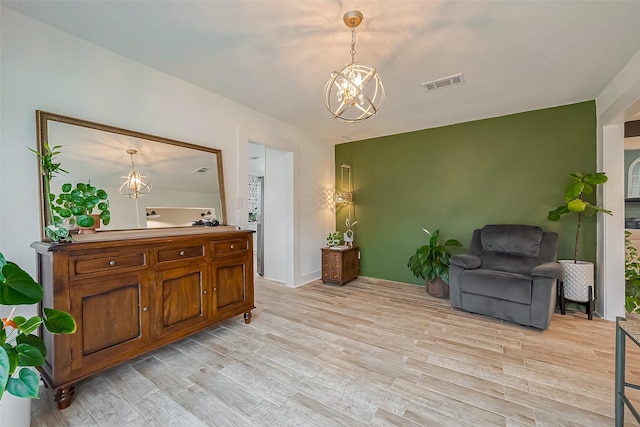 living area featuring light wood-type flooring, an inviting chandelier, and visible vents