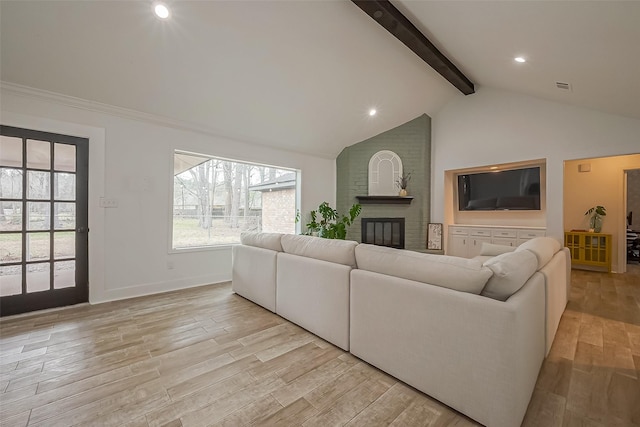 living room featuring beam ceiling, visible vents, a brick fireplace, light wood-type flooring, and baseboards