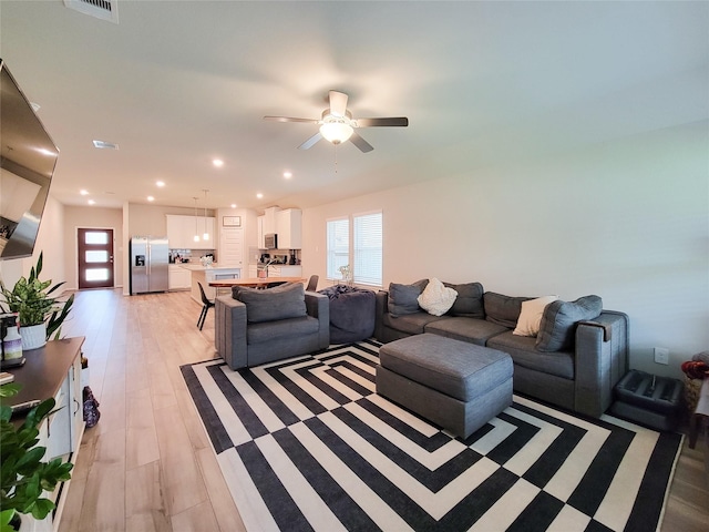 living room with light wood-type flooring, a healthy amount of sunlight, visible vents, and recessed lighting