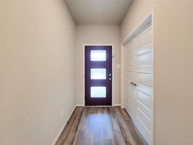 doorway to outside with baseboards and wood finished floors