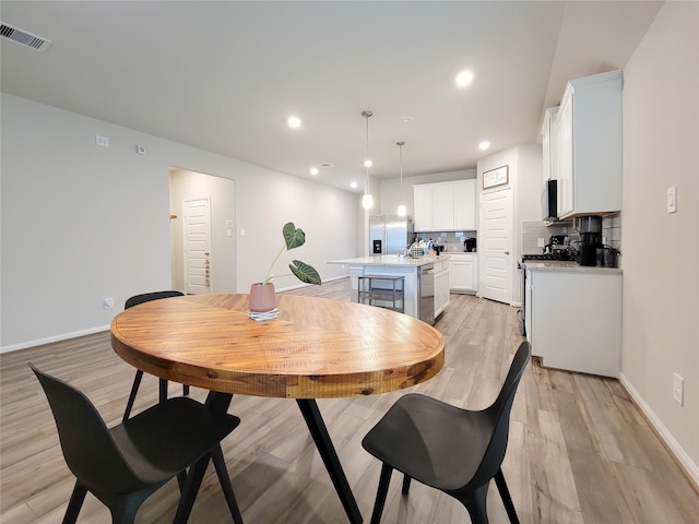 dining area featuring light wood-type flooring, baseboards, visible vents, and recessed lighting