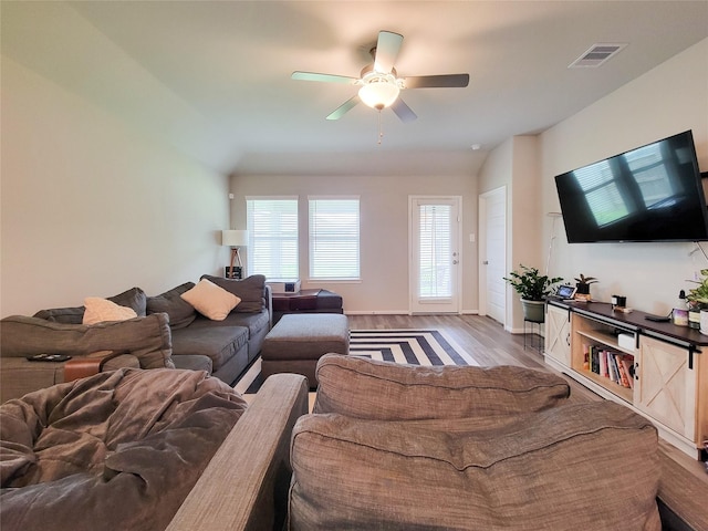 living area with a ceiling fan, visible vents, and wood finished floors