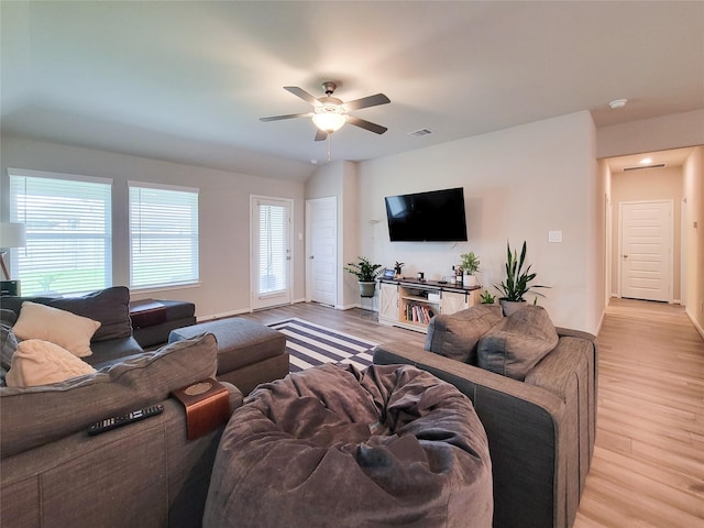 living room with light wood-type flooring, baseboards, visible vents, and a ceiling fan