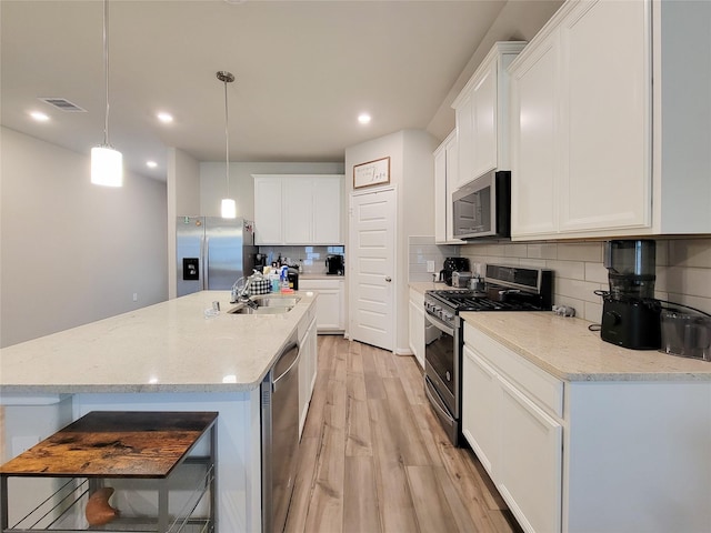 kitchen with visible vents, backsplash, appliances with stainless steel finishes, white cabinetry, and light wood-type flooring