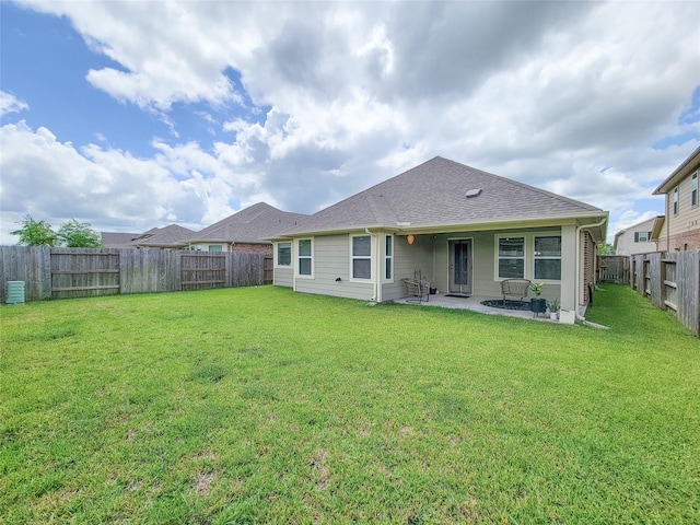 rear view of house featuring a shingled roof, a patio area, a lawn, and a fenced backyard