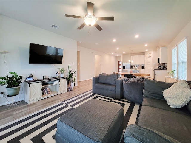 living room featuring light wood-style floors, visible vents, baseboards, and recessed lighting