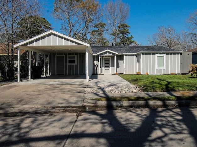 view of front of house with a carport, board and batten siding, a front lawn, and concrete driveway