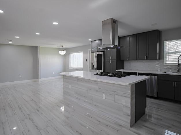 kitchen with stainless steel appliances, backsplash, exhaust hood, and a healthy amount of sunlight