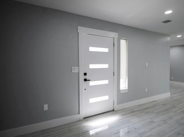 foyer entrance featuring recessed lighting, visible vents, light wood-style flooring, and baseboards