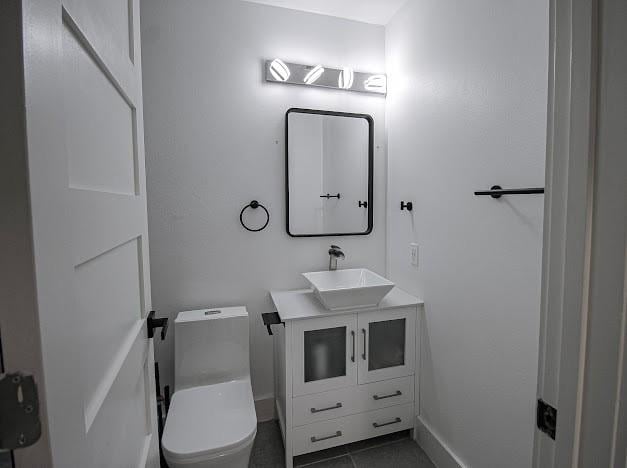 half bath featuring toilet, tile patterned floors, and vanity