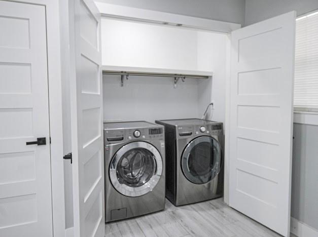 laundry area featuring laundry area, light wood-type flooring, and independent washer and dryer