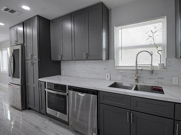 kitchen featuring visible vents, appliances with stainless steel finishes, gray cabinets, and a sink