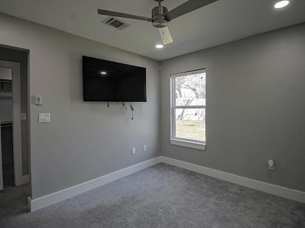 carpeted empty room with a ceiling fan, visible vents, and baseboards