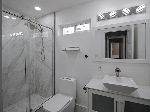 bathroom featuring a marble finish shower, vanity, and toilet