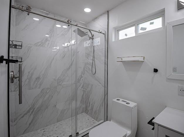 full bath featuring vanity, a marble finish shower, and toilet