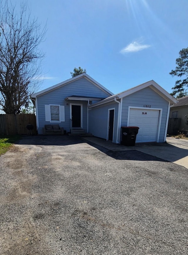 ranch-style house with aphalt driveway, entry steps, and fence