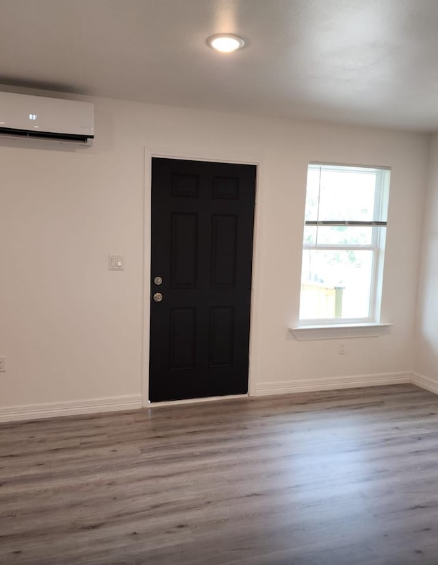 entrance foyer featuring wood finished floors, baseboards, and a wall mounted AC