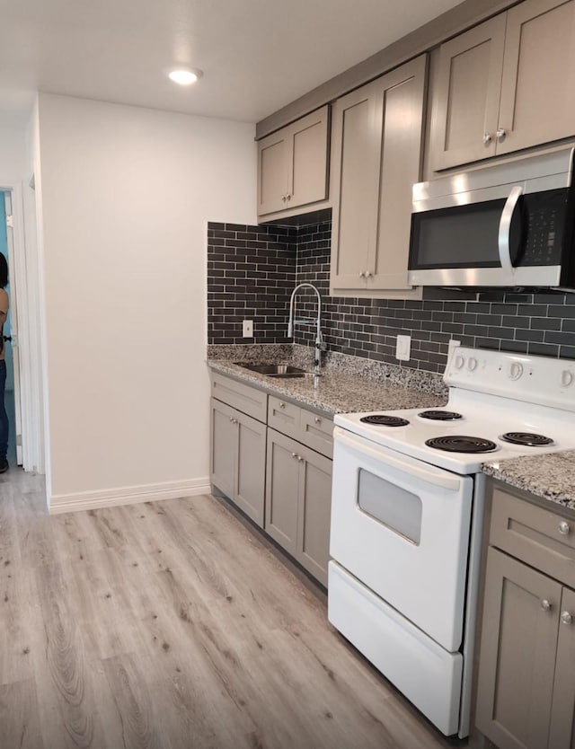 kitchen featuring a sink, stainless steel microwave, gray cabinets, and white range with electric cooktop