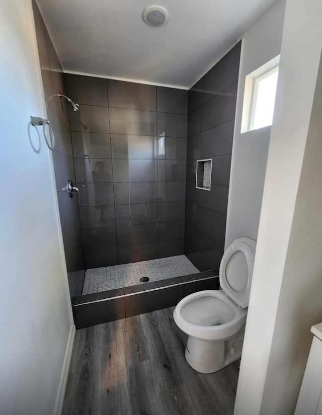 full bathroom featuring a shower stall, toilet, and wood finished floors