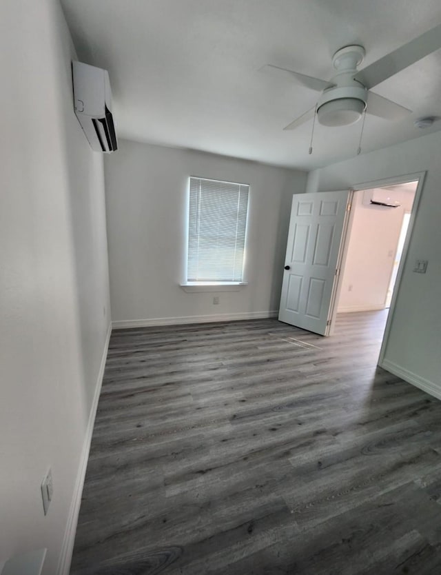 unfurnished room with ceiling fan, a wall mounted AC, wood finished floors, and baseboards