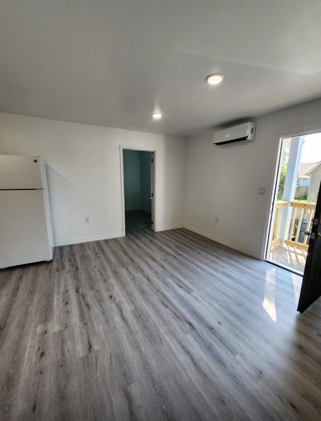 unfurnished room with a wall mounted air conditioner, wood finished floors, and baseboards