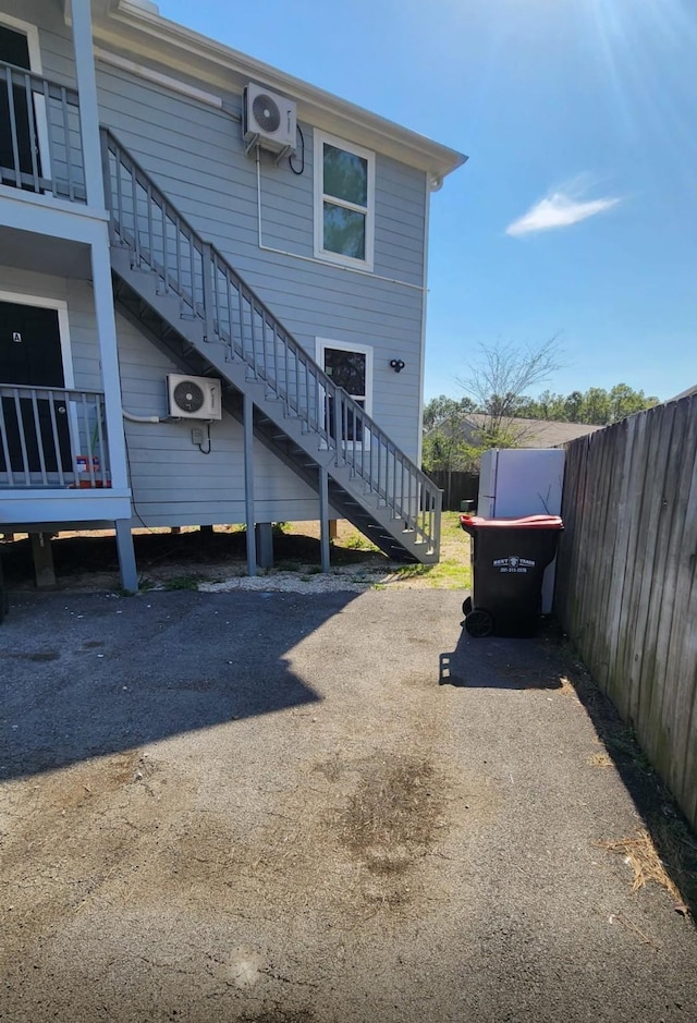 view of vehicle parking featuring driveway, ac unit, stairs, and fence