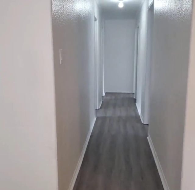 hallway featuring dark wood-style floors and baseboards