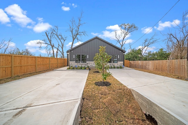 view of front of property featuring board and batten siding, fence private yard, and stone siding