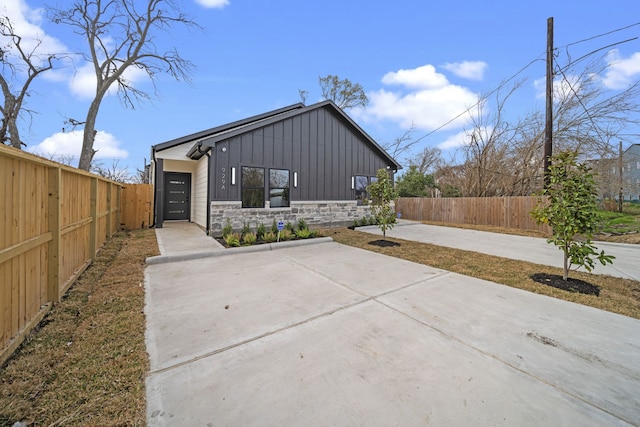 exterior space featuring board and batten siding, fence private yard, and stone siding