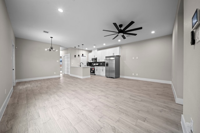 unfurnished living room with recessed lighting, ceiling fan with notable chandelier, a sink, baseboards, and light wood-type flooring