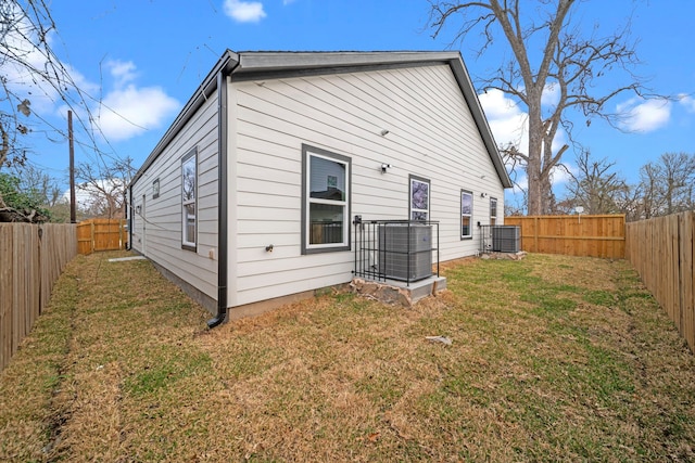 back of house with central AC, a yard, and a fenced backyard