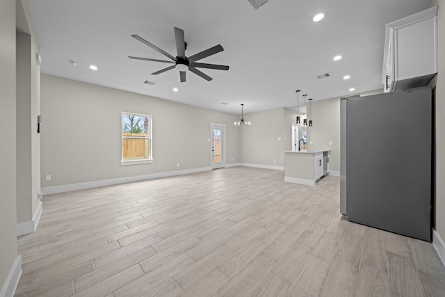 unfurnished living room featuring recessed lighting, ceiling fan with notable chandelier, visible vents, baseboards, and light wood finished floors