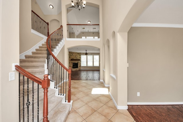 foyer entrance with arched walkways, a fireplace, a high ceiling, tile patterned flooring, and baseboards