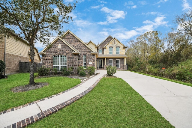 view of front of home with brick siding, a front yard, and fence