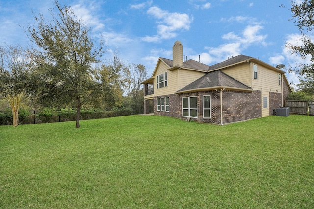 back of house with cooling unit, brick siding, fence, a lawn, and a chimney