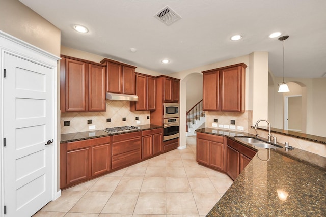 kitchen featuring arched walkways, under cabinet range hood, a sink, visible vents, and appliances with stainless steel finishes