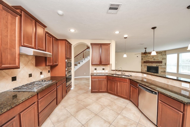 kitchen with stainless steel appliances, visible vents, a sink, dark stone countertops, and under cabinet range hood