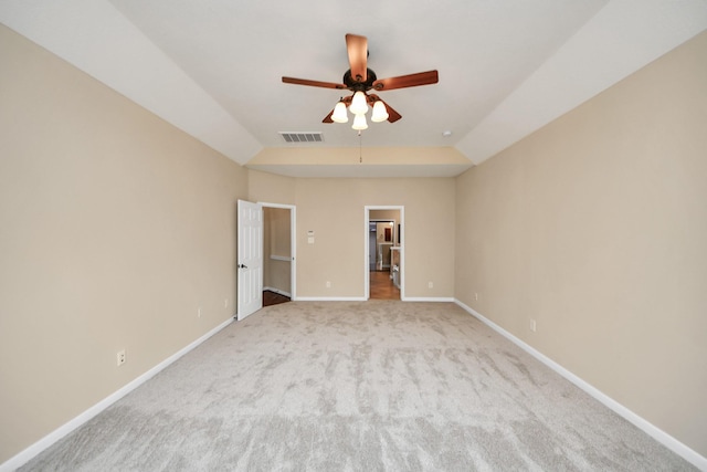 carpeted empty room featuring ceiling fan, vaulted ceiling, visible vents, and baseboards