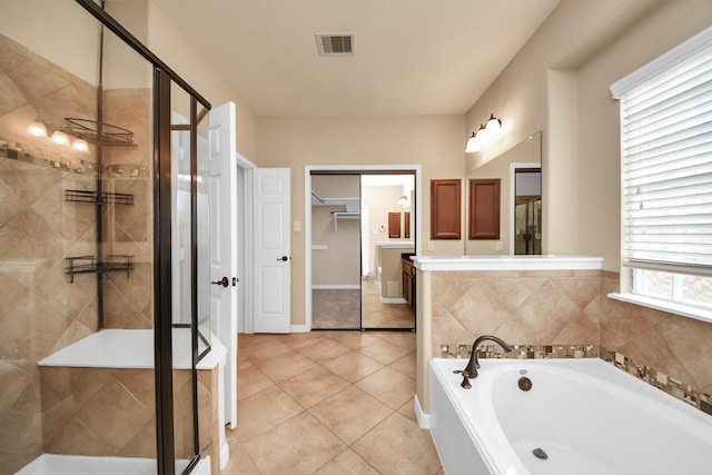 bathroom with a stall shower, visible vents, a walk in closet, and a bath