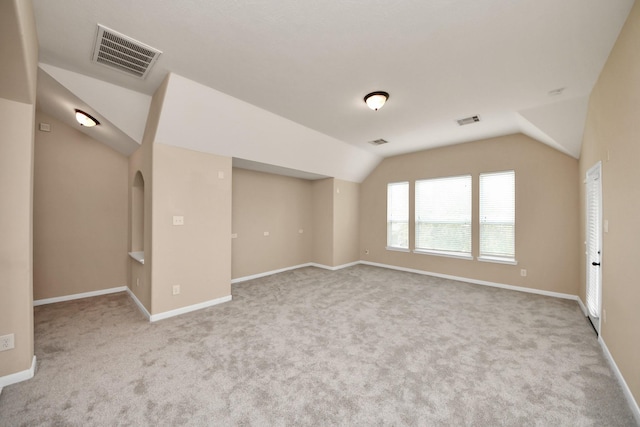 spare room with carpet floors, visible vents, and vaulted ceiling