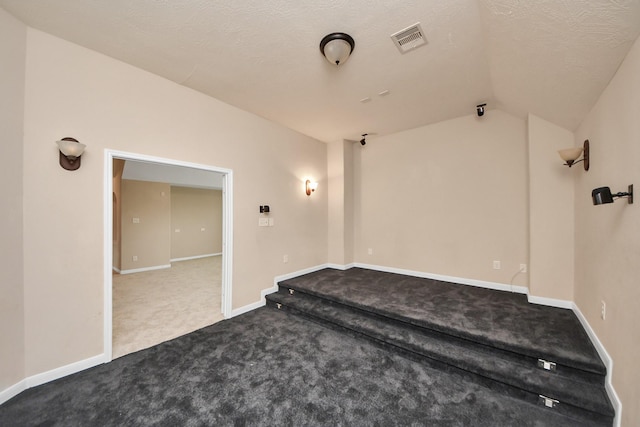 interior space featuring visible vents, baseboards, carpet, vaulted ceiling, and a textured ceiling