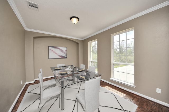 dining room with visible vents, crown molding, baseboards, and wood finished floors