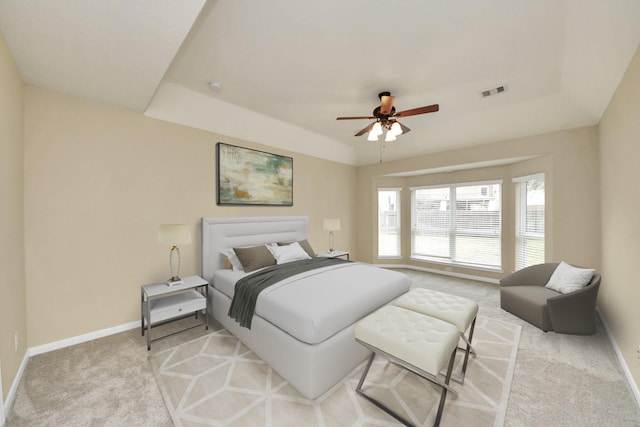 bedroom featuring a tray ceiling, light colored carpet, and baseboards