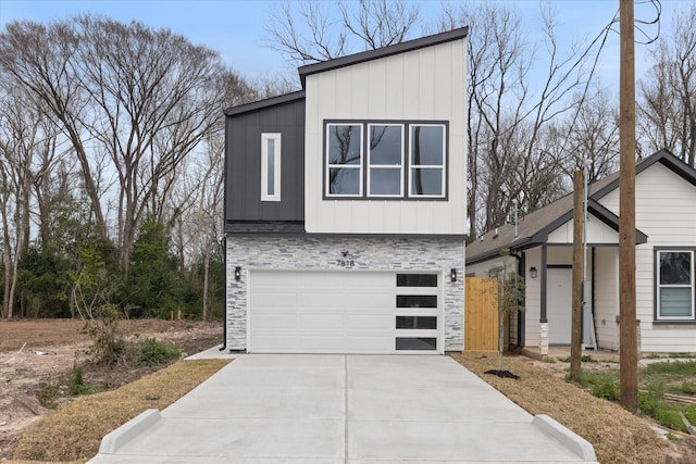 contemporary house featuring a garage, driveway, board and batten siding, and stone siding