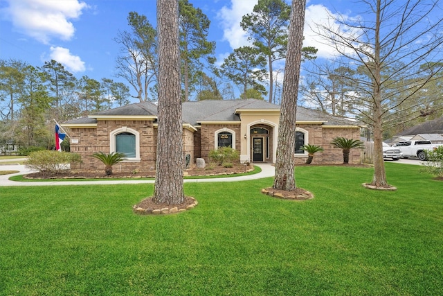 view of front of property featuring a front lawn, a shingled roof, and brick siding