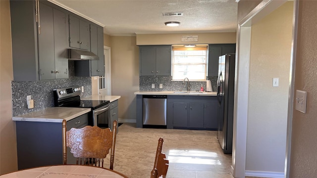 kitchen featuring stainless steel appliances, light countertops, gray cabinetry, a sink, and under cabinet range hood